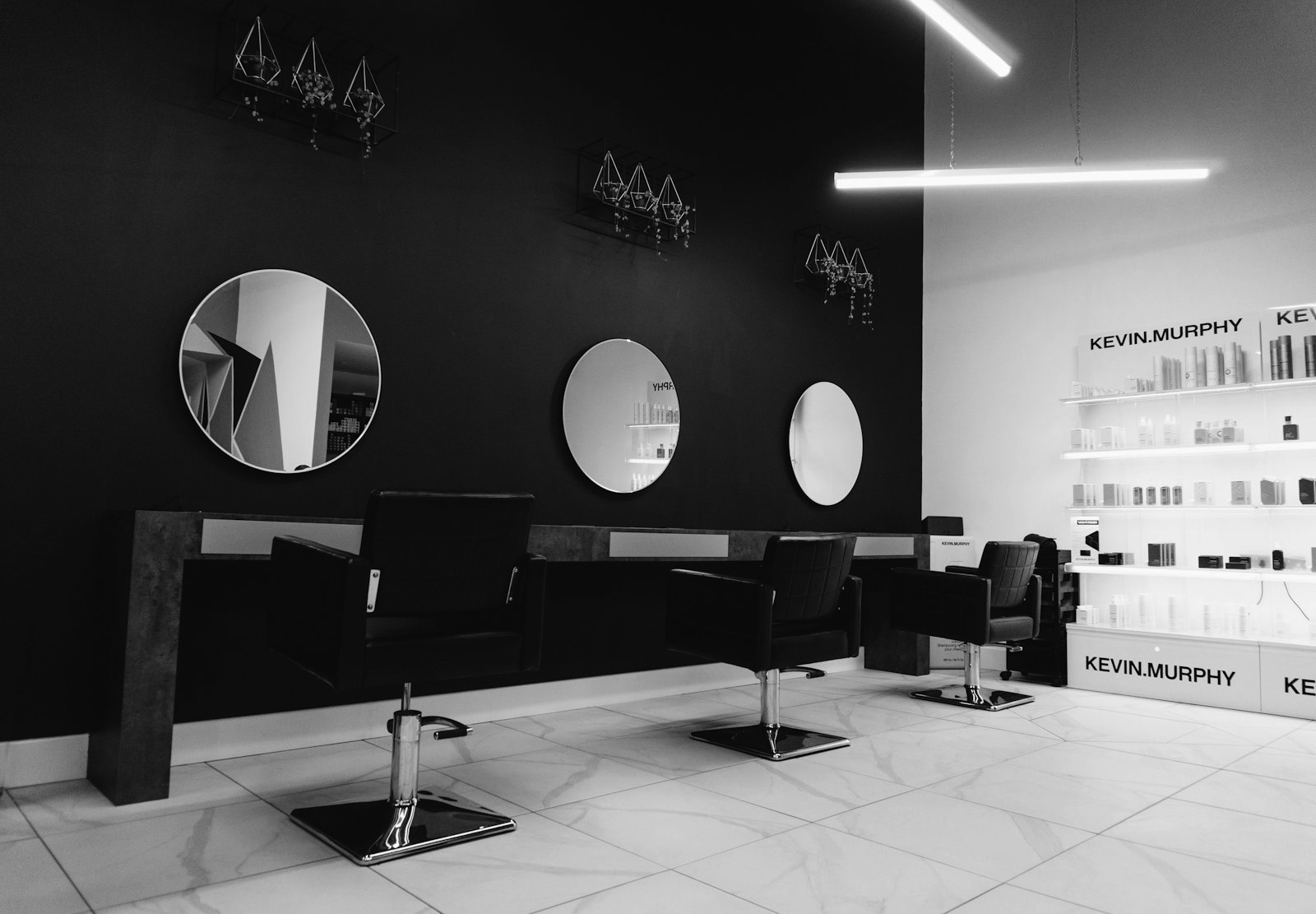 Intérieur d'un salon de coiffure moderne : fauteuils noirs alignés face à des miroirs ronds